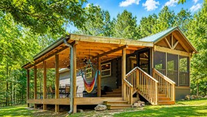 Een houten chalet met een veranda, een hangmat en een trap naar de hoofdingang.