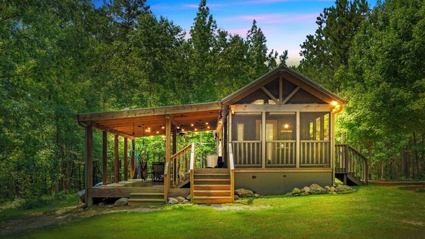 Een chalet met een overdekte veranda, houten trap en terras.