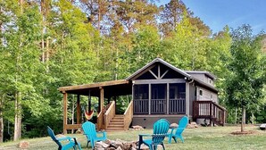 Een chalet met een veranda, buitenmeubels en uitzicht op het omliggende bos.