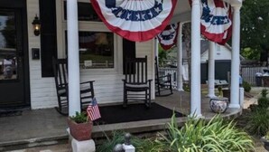 A house with a porch decorated with American flags. There are chairs and a small table on the porch. - The Gate House (Entire House) (Lancaster)