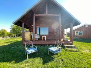 A rustic wooden cabin with a porch, two chairs, and a small table. - CABIN BY THE BLUFF OF KENAI RIVER WITH MOUNTAIN VIEW (Kenai)