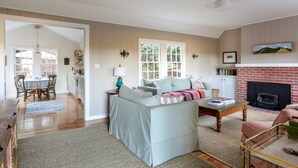 A spacious living room with a fireplace, a dining area with a table and chairs, and a kitchen in the background. - Baytree Cottage | Beautiful Stay w/ Amazing Views (Inverness)