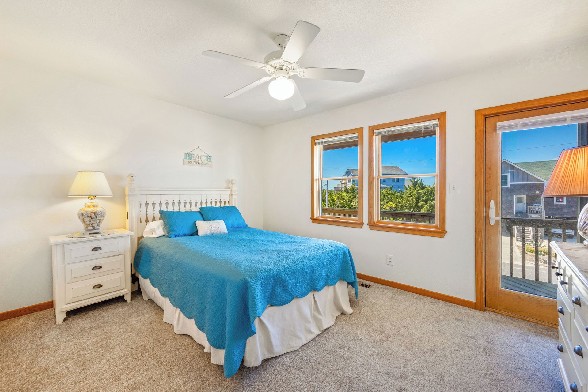 A bedroom with a bed, a nightstand, a lamp, a ceiling fan, and a window with a view.