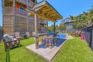 Un espace piscine doté d’une terrasse en bois, de tabourets de bar et de chaises longues.