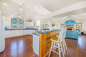 A spacious kitchen with a central island, wooden flooring, and a dining area with a blue sofa.