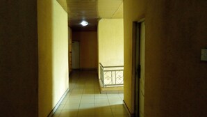 A narrow hallway with yellow walls and a tiled floor, leading to a door at the end. - Adebayowa Hotel (Lagos)