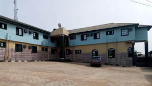 A building with a tiled facade, multiple windows, and a car parked in front. - Adebayowa Hotel (Lagos)