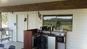 Une cuisine compacte équipée d’une cuisinière, d’un four et d’un réfrigérateur, d’un évier et d’une fenêtre donnant sur la campagne.
