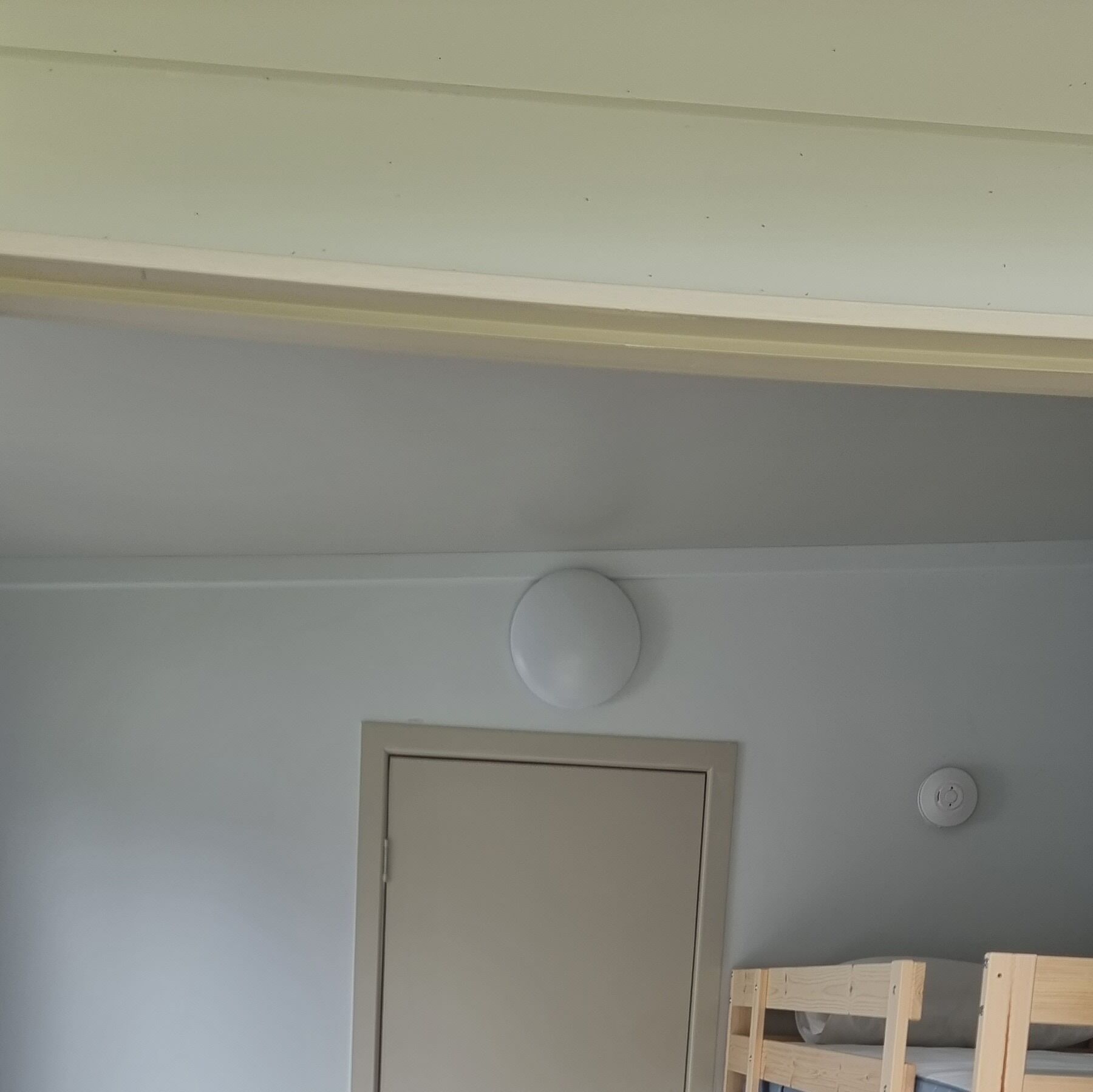 Una habitación con una puerta, un accesorio de luz y una cama litera.