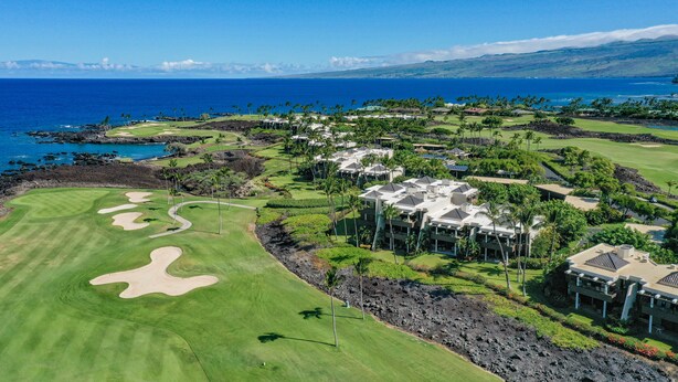Ein Golfplatz mit Bunkern, einem Clubhaus und Blick auf den Ozean.