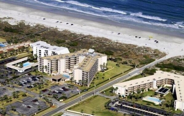 An aerial view of a coastal hotel complex with multiple buildings, parking areas, and a beach in the background. - Dir Ocean Front 2 BR/2 BA Condo (ST AUGUSTINE)