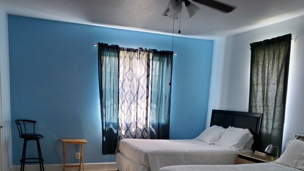 A room with two beds, a ceiling fan, a small table, and a chair. - $120.00 por noche .Full house 2/2<br>$100.00 cleaning fee<br>$30.00 Pet fee, per stay (Uvalda)