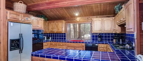 A kitchen with wooden cabinets, a blue tiled countertop, and a refrigerator.