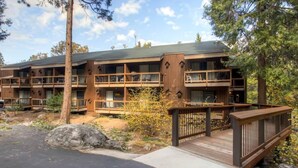 A multi-story lodge with balconies, wooden deck, and natural surroundings.