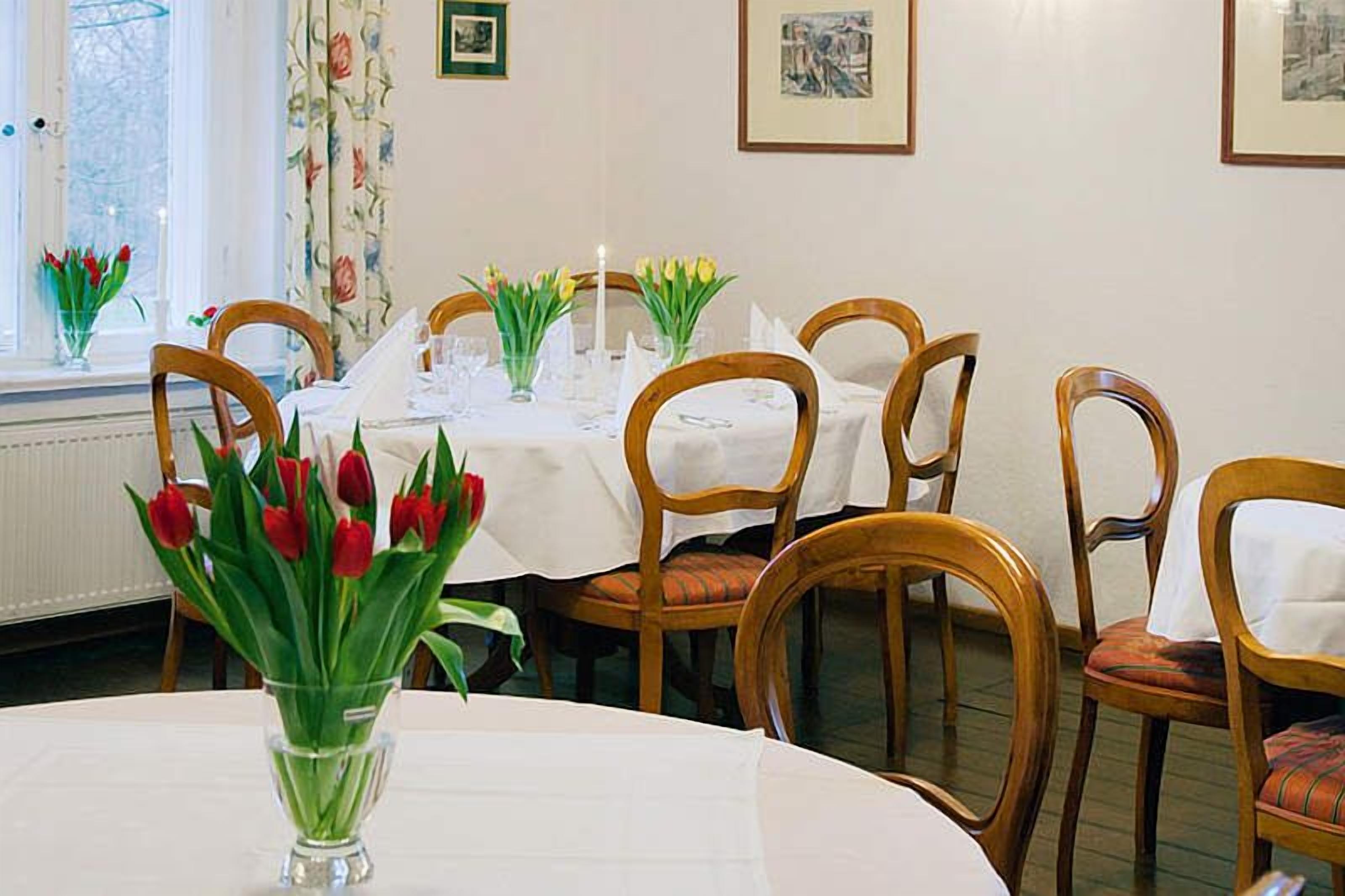 A dining area with round tables, chairs, and floral decorations.