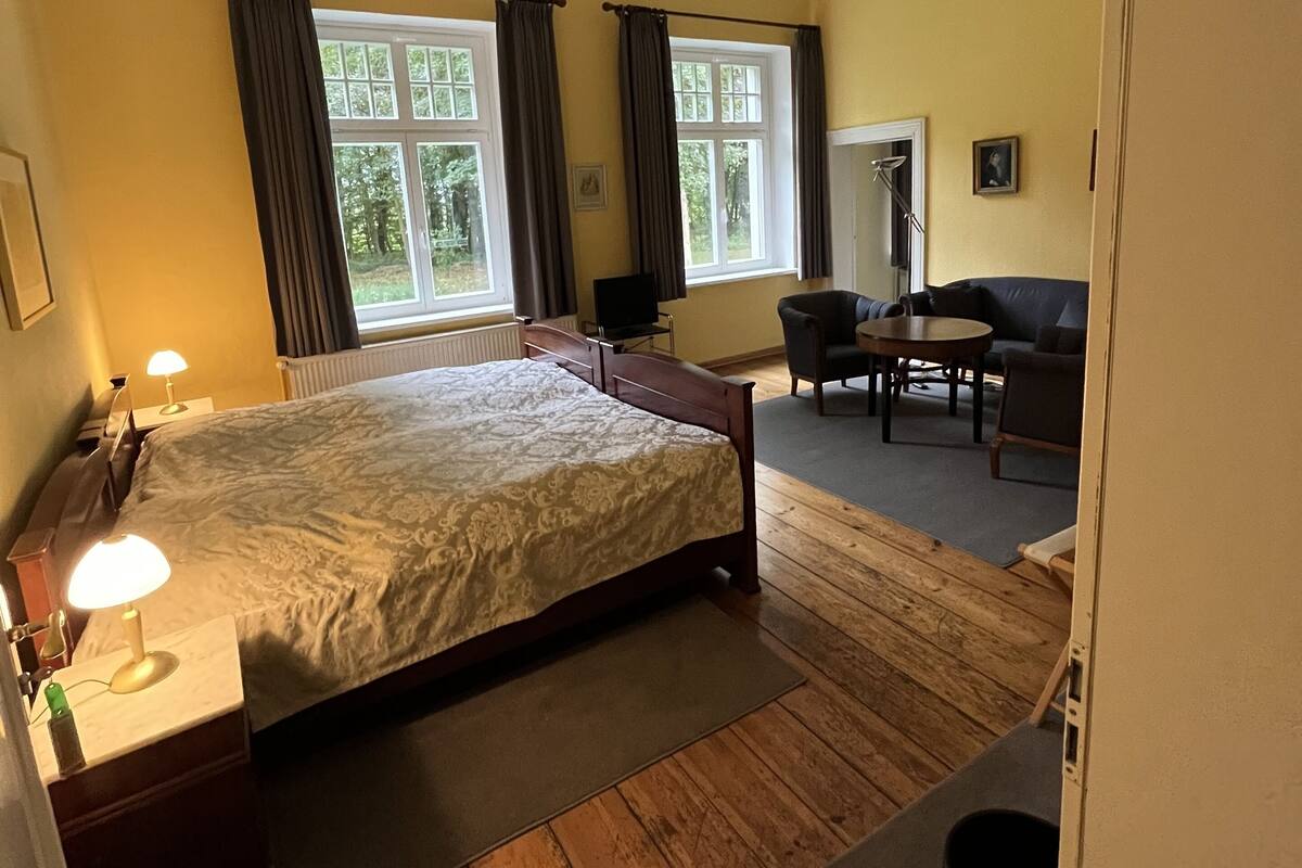 Ein Schlafzimmer mit Bett, Nachttischlampen, Schreibtisch und Stuhl.