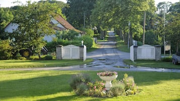 Una calle residencial con una entrada porticada, una cerca blanca de piquetes y un cantero de flores al frente.