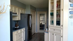 A kitchen with white cabinets, a black refrigerator, and a tiled floor.