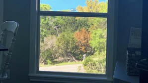 A room with a large window offering a view of a body of water and a forested area.