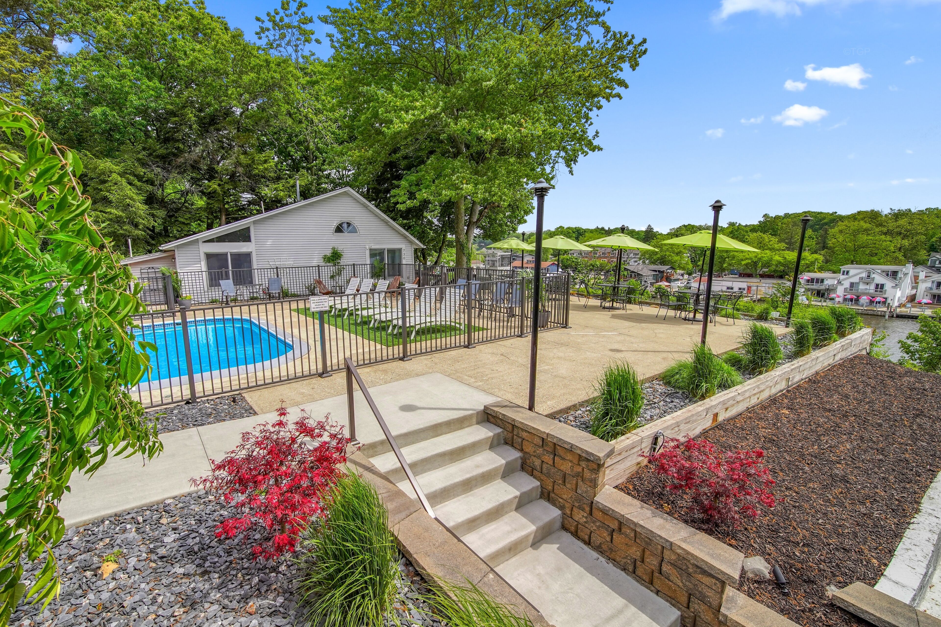 A residential area with a swimming pool, a covered patio, and a small house.
