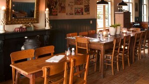 Ein gemütliches Restaurant mit Holztischen und -stühlen, einem Kamin und einem Spiegel an der Wand.