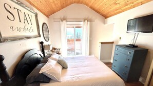 Un dormitorio con cama, cómoda, televisión y un cartel en la pared.