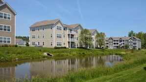 A residential building with multiple floors, balconies, and a small pond in front. - Rehoboth Beach Condo Elevator Pool Parking Clean (Rehoboth Beach)