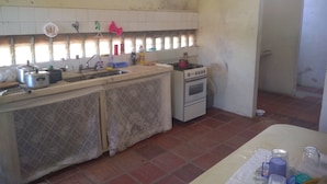 Una cocina con un lavamanos, estufa y alacenas. Hay ollas y sartenes sobre la encimera.