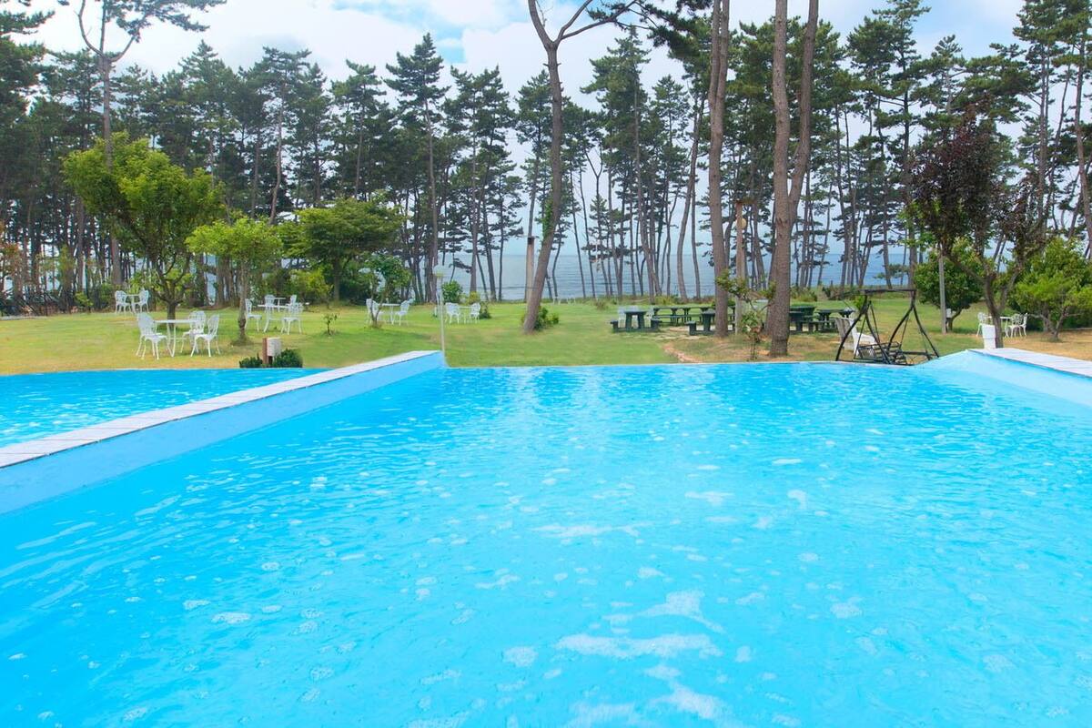 Una piscina con tobogán y zona de juegos al fondo.