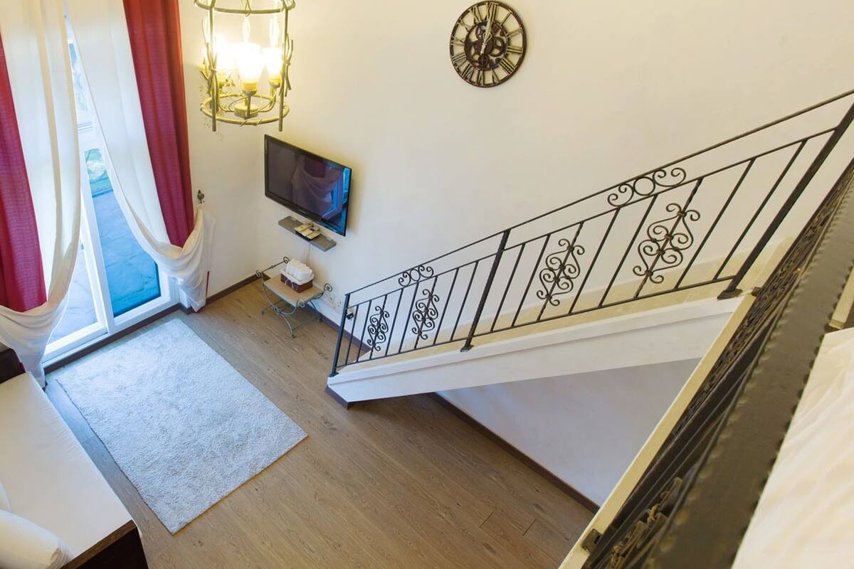 Una habitación con cama, televisión, reloj y escalera.