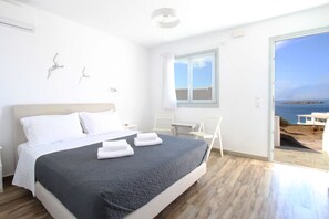 A modern bedroom with a bed, a desk, and a view of the sea. - Crystal View Mykonos (Mykonos)