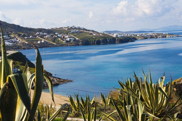 A coastal landscape with white buildings, a sandy beach, and a clear blue sea. - Crystal View Mykonos (Mykonos)