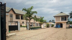 A gated residential area with paved walkways and a large tree in the center. - Bayse One Place Jericho (Ibadan)