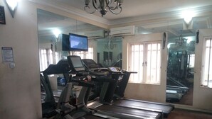 A gym with treadmills, a mirrored wall, and a television screen. - Bayse One Place Jericho (Ibadan)