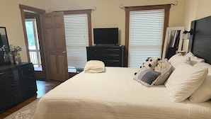 A bedroom with a bed, dresser, TV, and a door leading to a balcony.