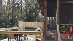 A wooden deck with a table and chairs, a hot tub, and a covered seating area.