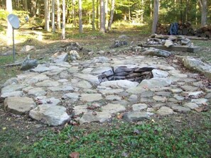 Un hogar de piedra rodeado de rocas en un área boscosa.