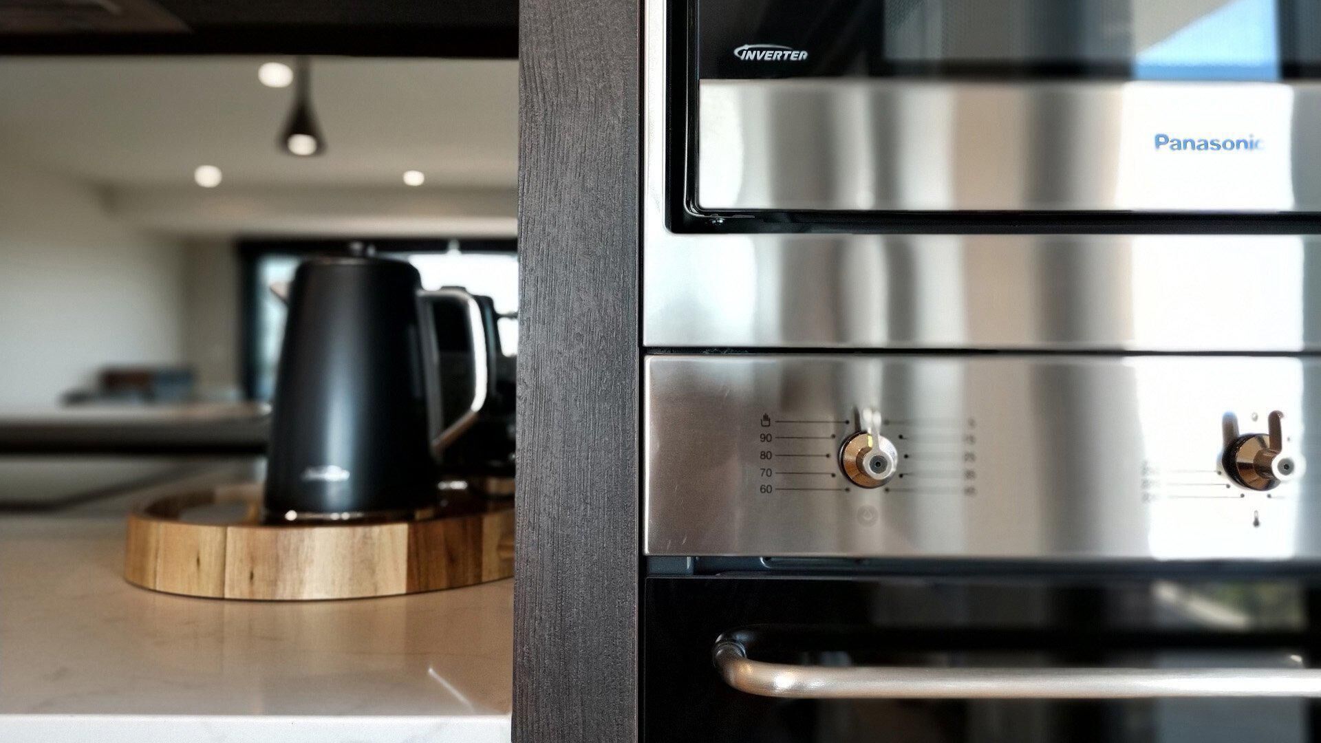 A kitchen with a stainless steel range hood, a coffee maker, and a wooden tray.