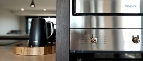 A kitchen with a stainless steel range hood, a coffee maker, and a wooden tray.