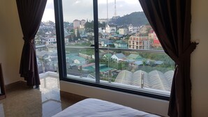 A room with a large window offering a view of a cityscape. - An Nhien Hotel (Xuan Huong - Da Lat)