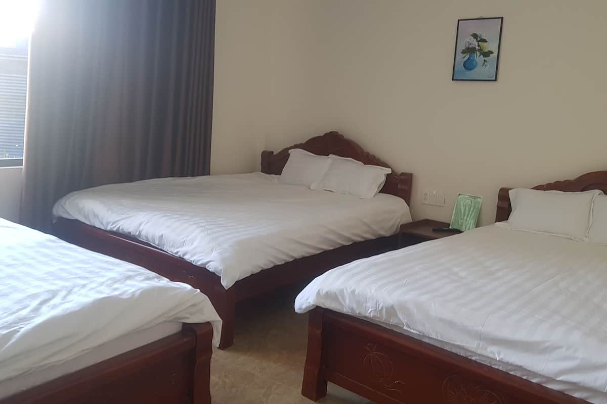 Ein Hotelzimmer mit zwei Einzelbetten, einem Nachttisch, einer grünen Vase und einem gerahmten Bild an der Wand.
