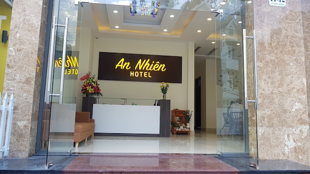 The reception area of An Nhien Hotel with a modern design, including a reception desk, a sofa, and a wall-mounted sign. - An Nhien Hotel (Xuan Huong - Da Lat)