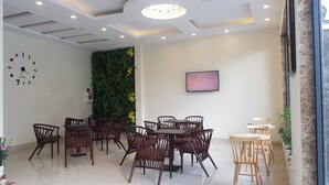 A conference room with a round table and chairs, a clock on the wall, a fire extinguisher, and a TV screen. - An Nhien Hotel (Xuan Huong - Da Lat)