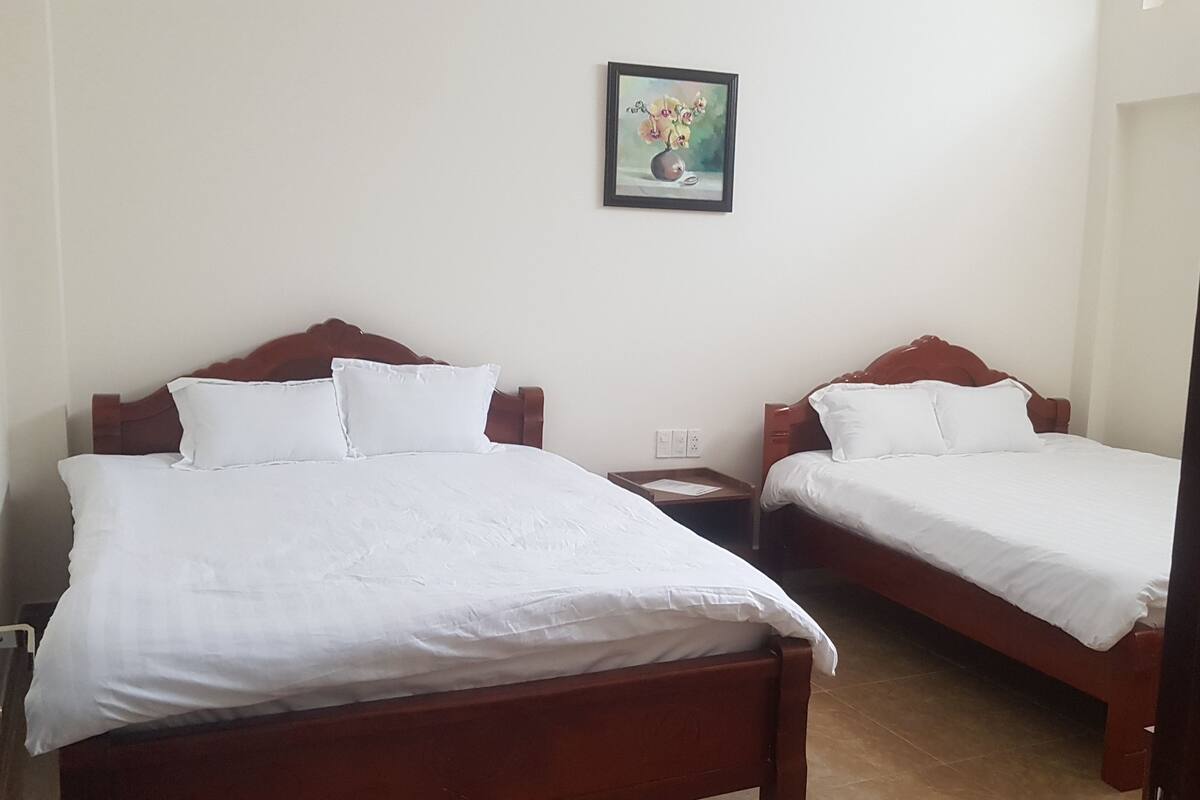 Ein Zimmer mit zwei Holzbetten, weißer Bettwäsche, einem Nachttisch und einem gerahmten Bild an der Wand.
