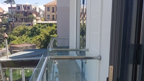 A modern balcony with a glass railing, a sliding door, and a view of the surrounding buildings. - An Nhien Hotel (Xuan Huong - Da Lat)