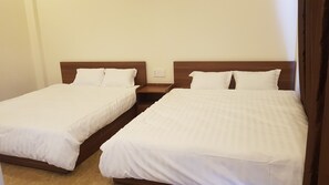 Two single beds with wooden headboards and white bedding in a hotel room.