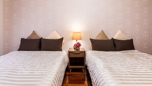 Une chambre d’hôtel avec deux lits, une table de chevet avec une lampe et un arrangement floral.