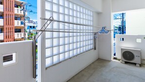 Une pièce dotée d’une grande fenêtre, d’un étendoir et d’un appareil de climatisation.
