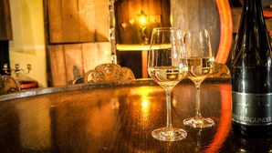 Un bar con dos copas de vino y una botella de vino Weissburgunder sobre una mesa de madera.