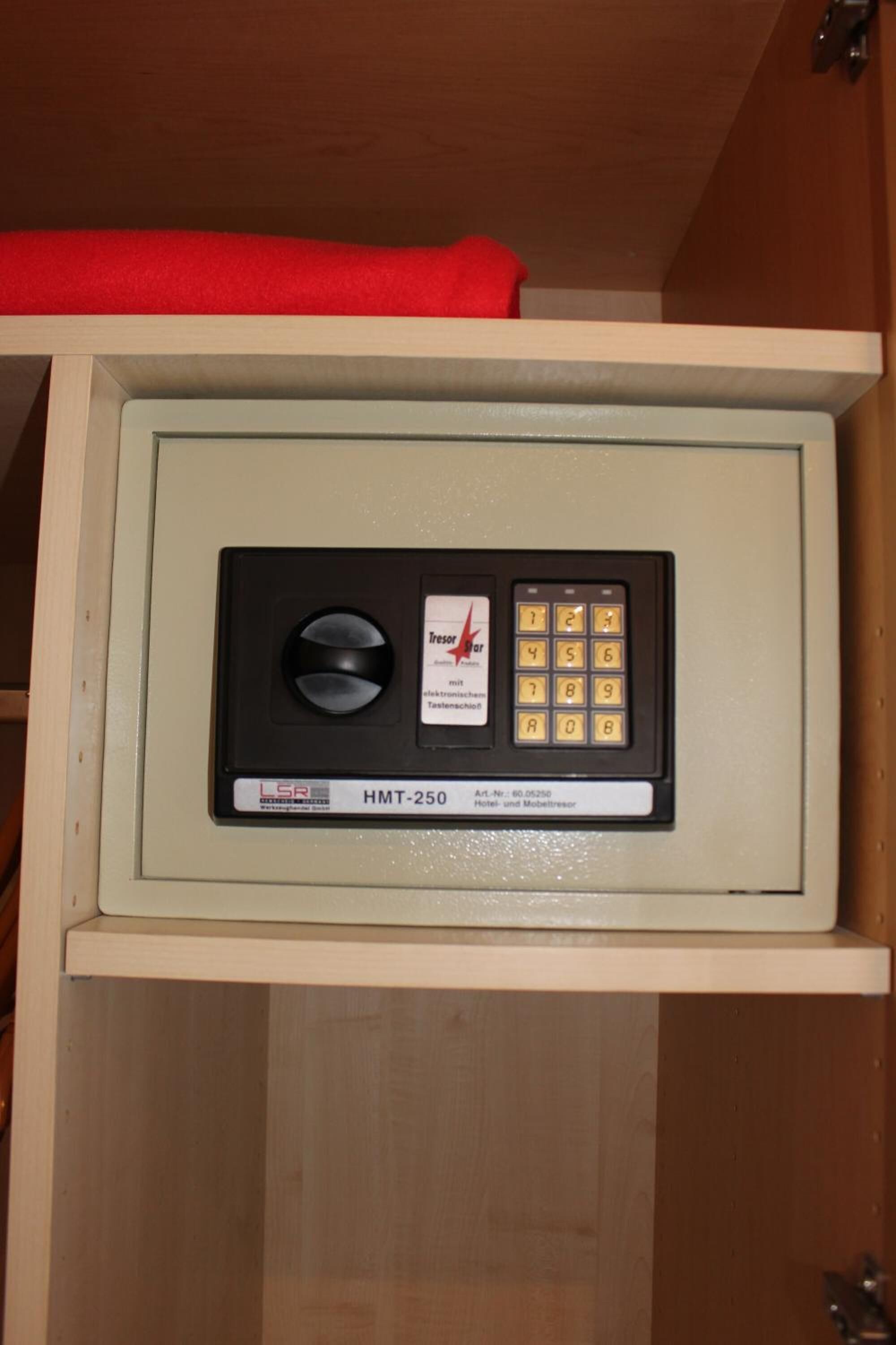 A safe with a keypad and a lock mechanism inside a wooden cabinet.